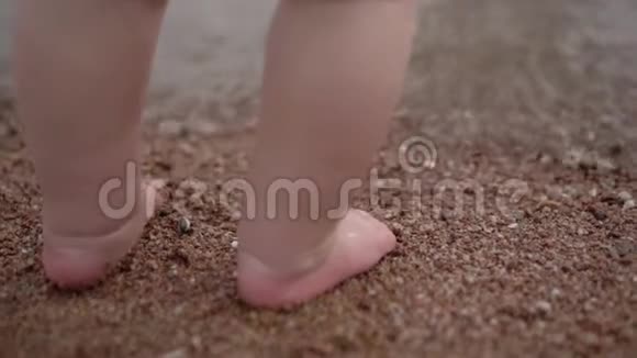 小宝宝的小腿站在沙滩上的沙滩上视频的预览图