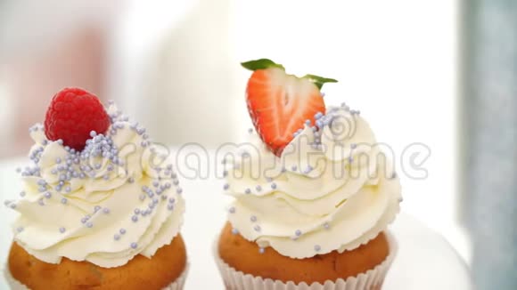 年轻漂亮的金发女人带着草莓装饰美味的纸杯蛋糕视频的预览图