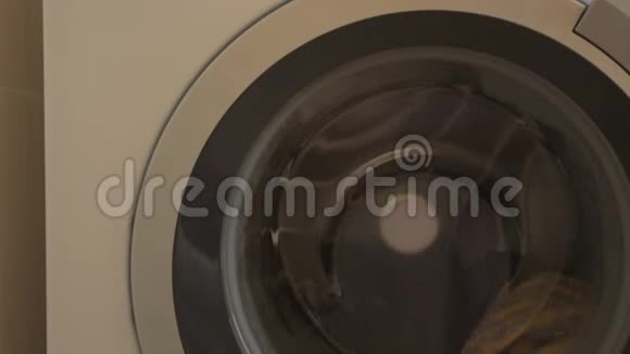 白色洗衣机的圆门工作并与彩色衣服旋转洗衣机洗毛巾视频的预览图