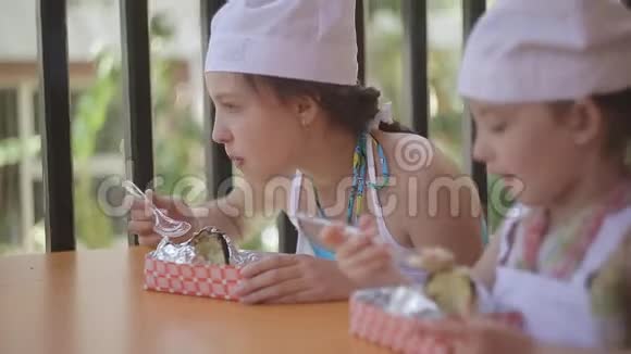 两个姐妹穿着厨师的衣服在餐桌上吃他们的土豆视频的预览图