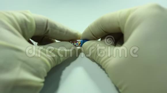 双手戴医用手套用彩色球打开胶囊视频的预览图
