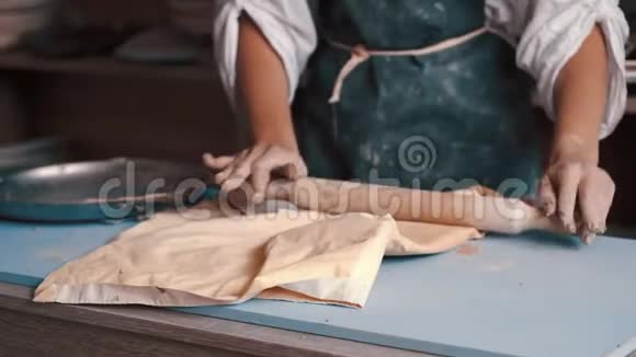 一个女陶工穿着围裙用擀面杖准备和滚泥视频的预览图