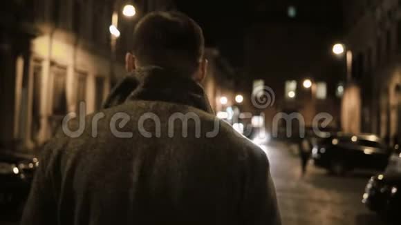 晚走在黑暗的街道上的年轻时尚男子的后景独自在晚上走视频的预览图