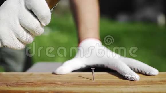 戴着工作手套的人在户外敲钉子在后院修理家具堵塞钉子木制品视频的预览图