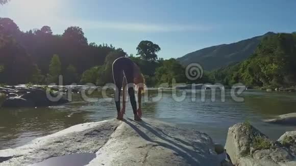 背面观景女孩做瑜伽石对河视频的预览图