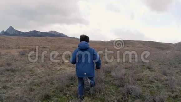 一个带着石头的男孩在田野对地平线慢速视频视频的预览图