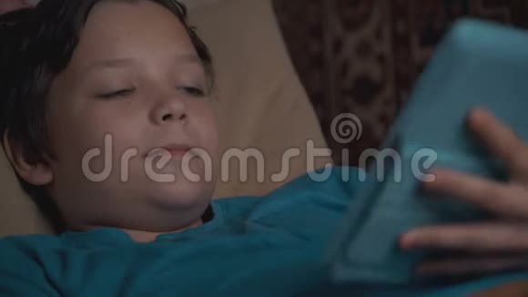 摄影男孩使用平板电脑躺在沙发上视频的预览图