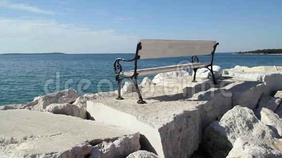 坐在海里海滩上的岩石上的白色长凳美丽的长凳白色岩石和石头与蓝色亚得里亚海视频的预览图