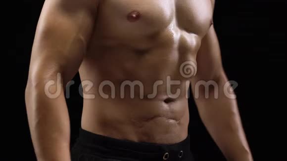 男人在黑色背景下展现肌肉强健的身体特写视频的预览图