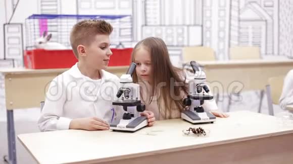 孩子们在学校实验室里看显微镜学习生物学化学学校科学概念视频的预览图