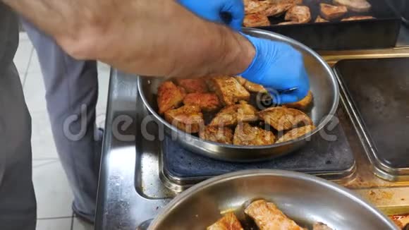 鸡肉腌制后放入煎锅内煎炸双手厨师翻蓝手套厨房餐厅从上面看肉类视频的预览图