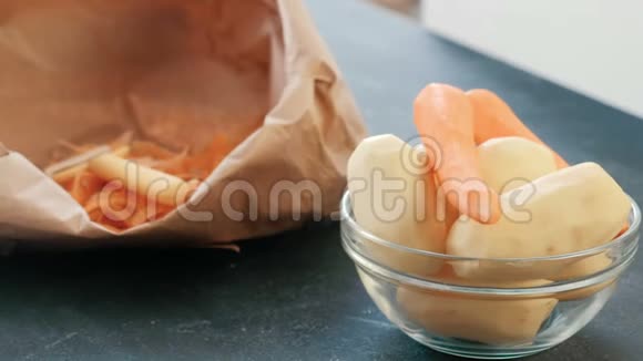 特写镜头把土豆和胡萝卜削皮放在碗里背景中的生态袋视频的预览图