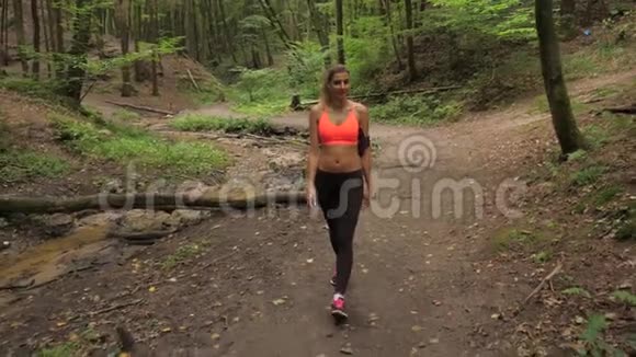 一个皮肤黝黑的女人穿着慢跑服静静地走在林间小路上视频的预览图