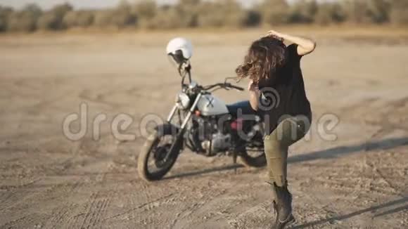 年轻漂亮的女人在日落或日出时在沙漠里跳舞背景摩托车视频的预览图
