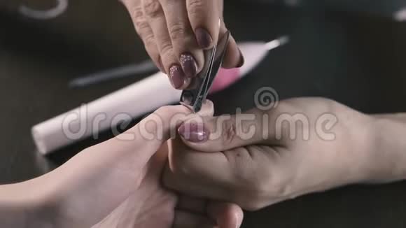 将指甲油涂在女性指甲上的美容师的特写镜头关注重点视频的预览图