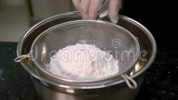 酋长戴着白色硅胶手套的手在厨房里筛面粉视频的预览图