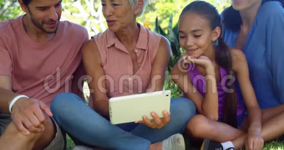 一家人在公园里看数码平板电脑视频的预览图