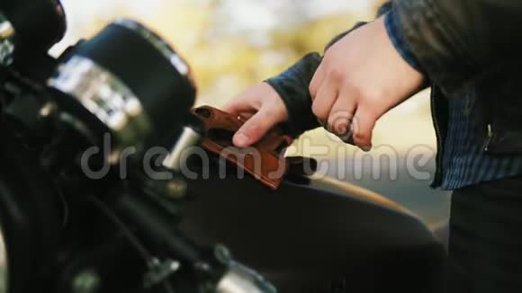 一个不可辨认的摩托车手带着棕色的皮手套戴着特殊的皮手套坐在车上视频的预览图