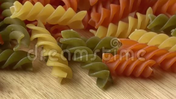 未煮熟的三色意大利面食木制桌子上干意大利面食视频的预览图