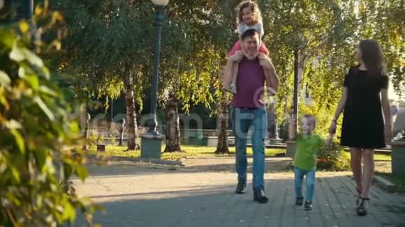 夏季傍晚在公园散步的健康家庭爸爸妈妈女儿和小男孩慢动作视频的预览图