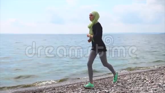 在卵石海滩慢跑训练的穆斯林女孩视频的预览图
