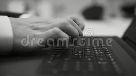 黑白电影中的白人商人坐在桌旁用手提电脑键盘打字视频的预览图