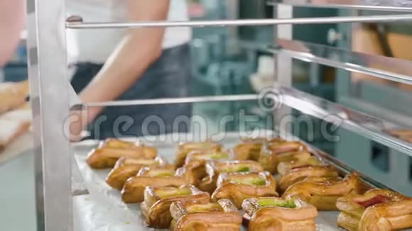 面包师在商业面包店的钢架上放一个带新鲜面包的托盘视频的预览图