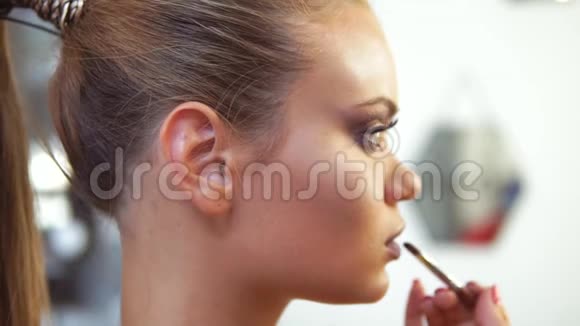 专业化妆师用特殊的画笔在白种人模特上涂口红的特写镜头视频的预览图