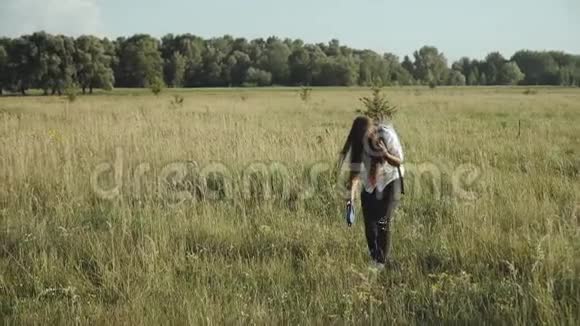 女人在田野里系鞋带自然行走慢动作视频的预览图