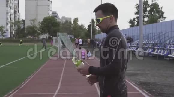 主题体育与健康年轻的高加索男性运动员在一个城市体育场的运动瓶里饮水视频的预览图