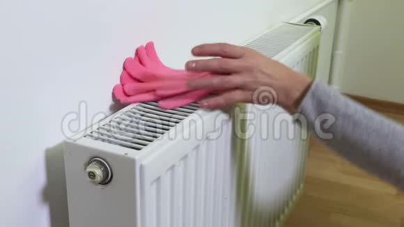 女人把粉色手套和豆子放在散热器上视频的预览图