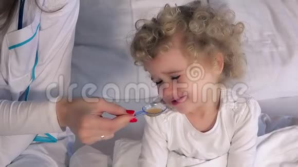 女医生给坐在床上的小病女孩一勺糖浆视频的预览图