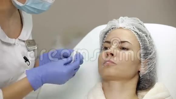 美容师在隆唇手术前将麻醉膏涂于病人嘴唇上视频的预览图