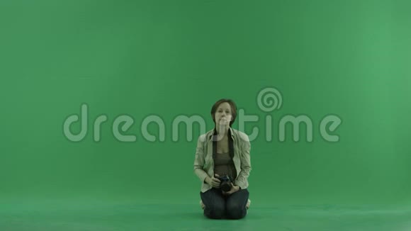 坐着的年轻女子正在绿色屏幕上拍照视频的预览图