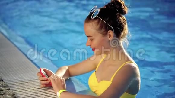 穿着泳衣的年轻女子在手机上为社交网络检查照片视频的预览图