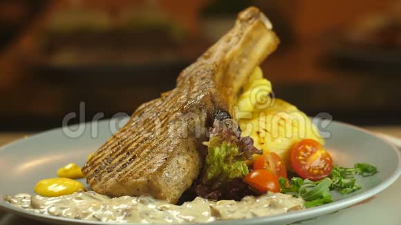 骨头烤烤肉上的牛肉土豆泥和蔬菜在盘子里旋转视频的预览图