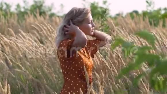 迷人的有趣的嬉皮金发女人在田野在日落时在户外玩得很开心慢动作女性在田里旋转视频的预览图