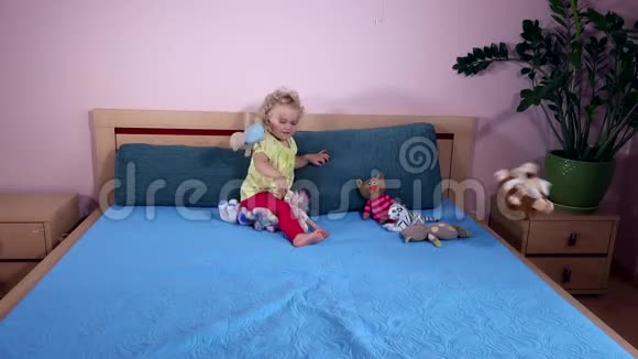 可爱的女孩在床上扔长毛绒玩具视频的预览图