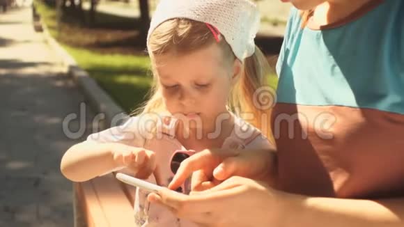 小女孩正在玩一部智能手机躺在她妈妈的手中视频的预览图