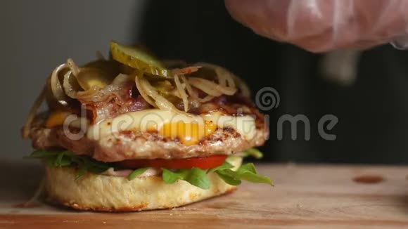 煮大汉堡的过程是专业厨师特写把黄瓜和奶酪放在面包上视频的预览图