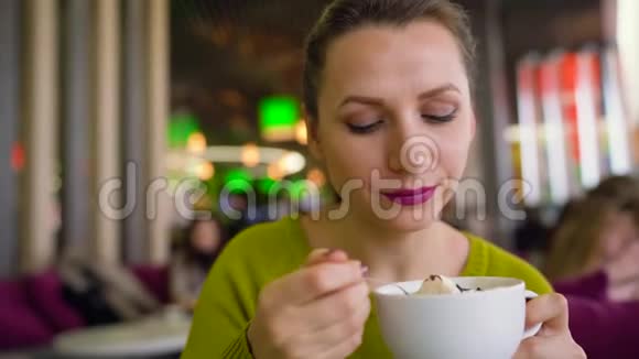 女人在咖啡馆里喝着加奶油的咖啡喝着加勺子的巧克力糖浆和朋友聊天视频的预览图