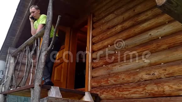 一个在木制露台上打电话的年轻人视频的预览图