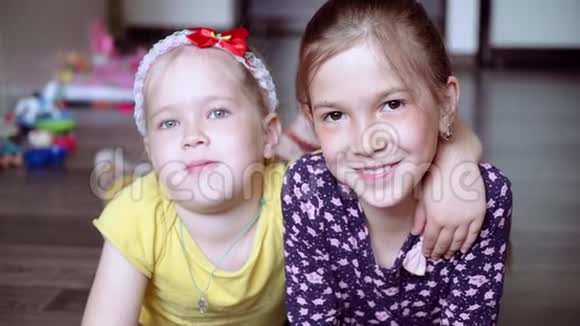 两个小女孩躺在地上对着镜头微笑两个姐妹女孩们在笑视频的预览图