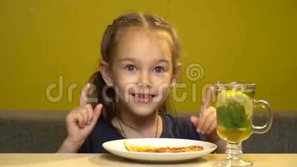 咖啡馆里的小女孩正在用手吃比萨饼桌上有一杯茶和薄荷蜂蜜和柠檬视频的预览图