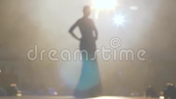 在聚光灯下苗条的模特穿着优雅的长裙走在T台上视频的预览图