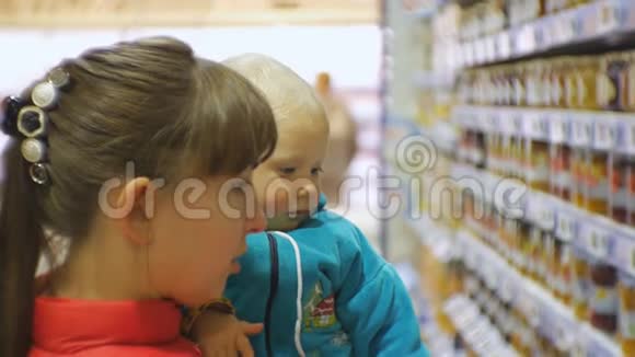 可爱的白种人妇女选择婴儿食品在超市抱着婴儿怀里妈妈和宝宝的特写镜头视频的预览图