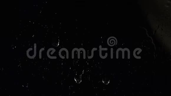 透明的水滴顺着玻璃流下来白色的小颗粒漂浮在黑色的背景上库存数据视频的预览图