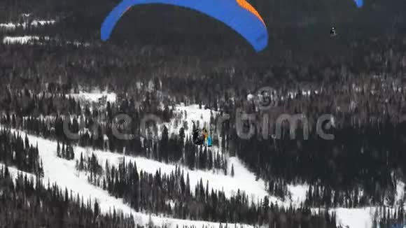 冬天在白雪覆盖的群山的背景下滑翔伞视频的预览图