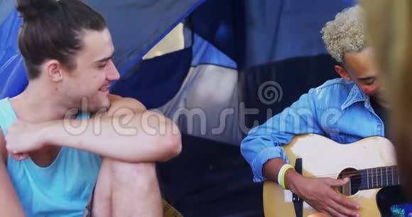 男人在音乐节上为朋友弹吉他视频的预览图