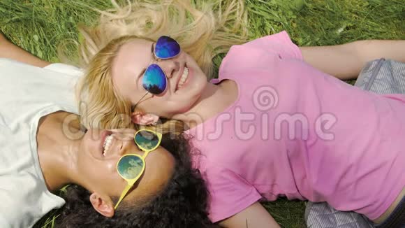 两个女朋友躺在公园的草地上享受夏天的周末友谊视频的预览图